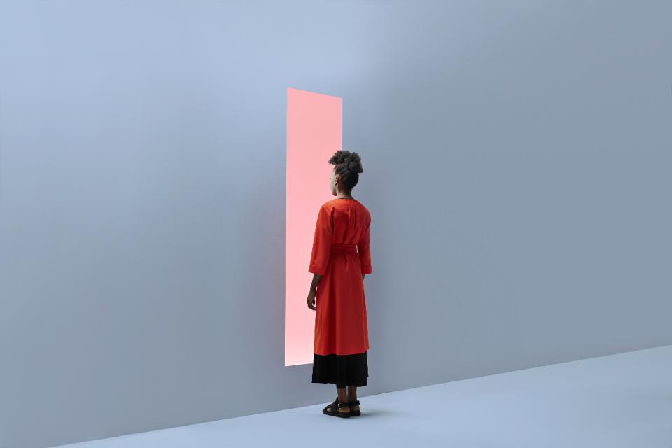 Woman standing in front of rectangular opening in coloured wall